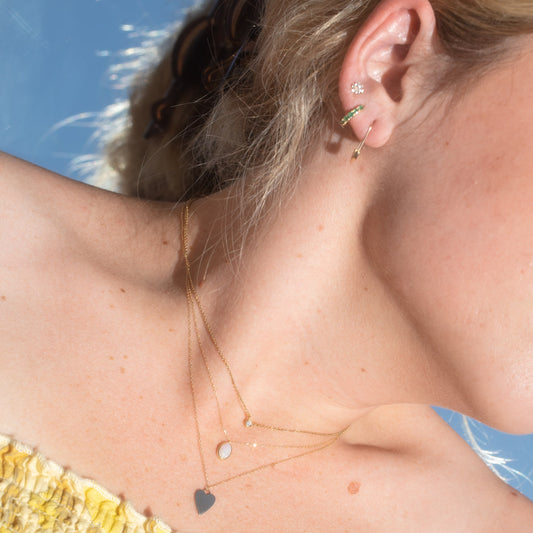 solid gold jewelry on figure in the sun with a sky background