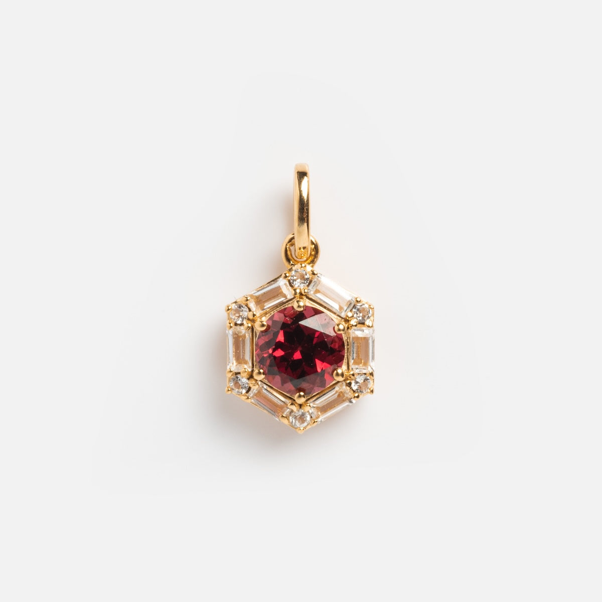 The Vintage Inspired Pendant Charm features a gold hexagonal design with a central red gemstone, clear baguette stones, and round diamonds, shown on a white background.