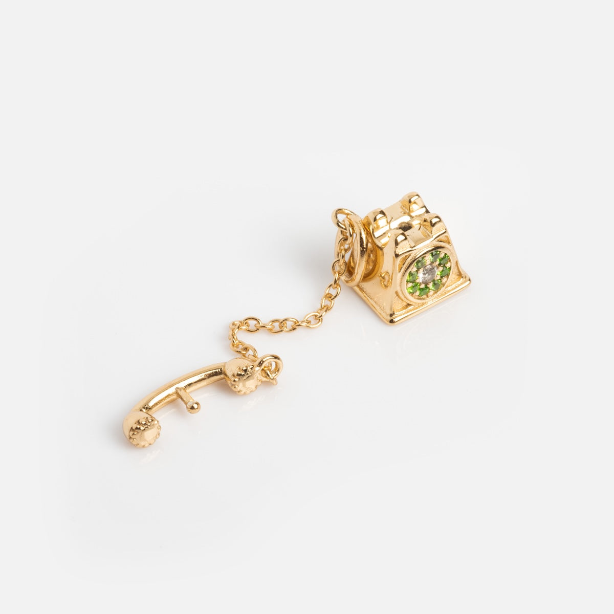 The Vintage Inspired Trinket Charm is a gold vermeil rotary telephone charm with a green gemstone center and a dangling receiver, evoking a Period Piece. It’s elegantly displayed on a white background.