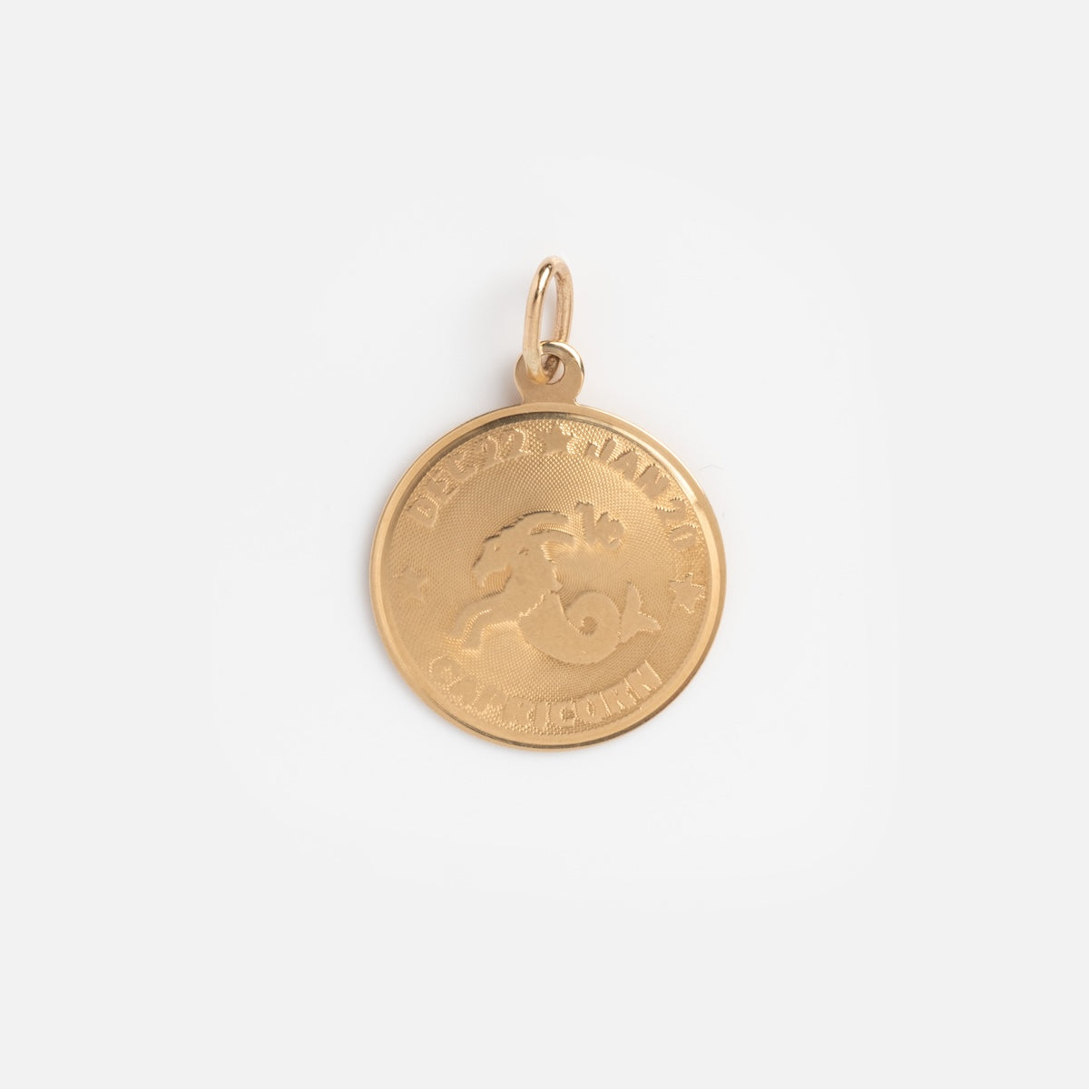 A round solid yellow gold Vintage 14k Capricorn Coin Charm features an embossed Capricorn design in the center, text and small star symbols around the edge, and a small loop for hanging—a charming piece of vintage jewelry.