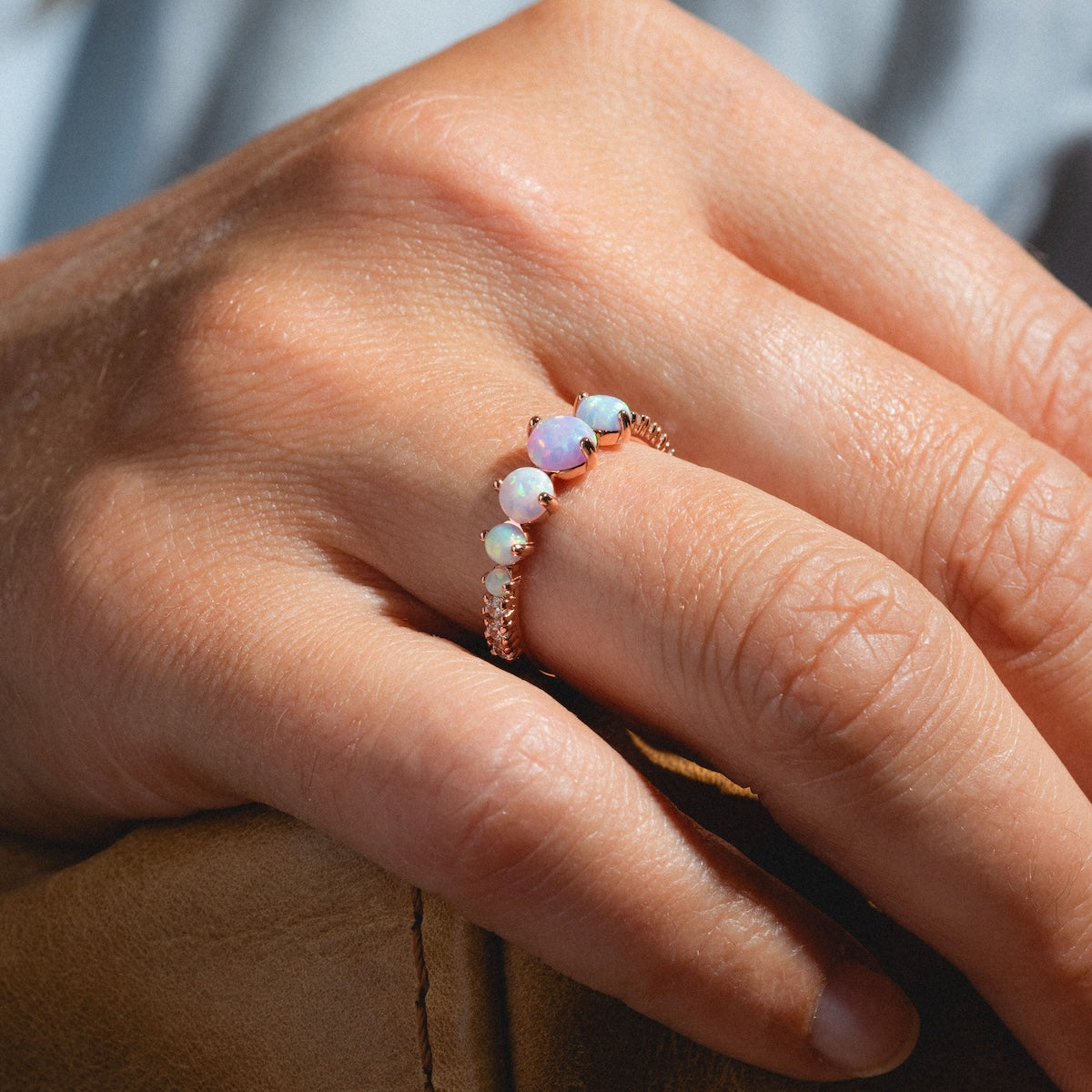 A close-up of a hand wearing the Pastel Opal Shooting Star Ring in rose gold vermeil. The blurred background highlights the opal gemstones and elegant shooting star design of this stylish ring.