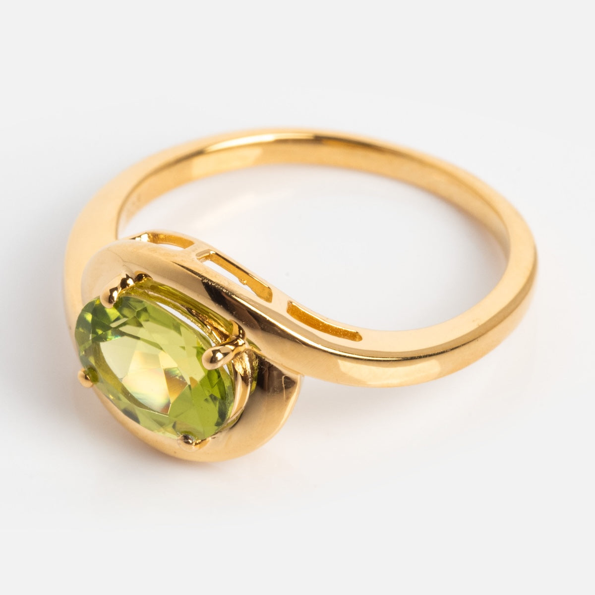 The Peridot Poetry Statement Ring showcases an oval-cut green peridot in a modern, asymmetrical 14k gold vermeil setting, displayed against a light background.