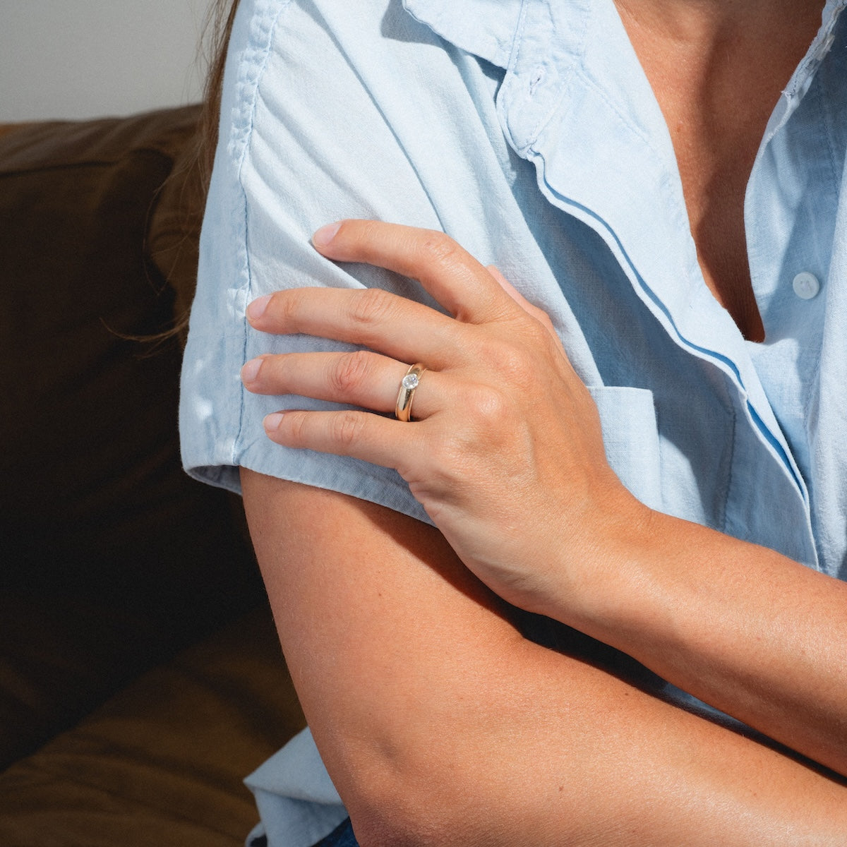A person in a light blue short-sleeve shirt sits with crossed arms, showcasing the Vintage 14k 1900’s Euro Cut Diamond Classic Band Size 7.5 on their finger. Only their torso and hand are visible.