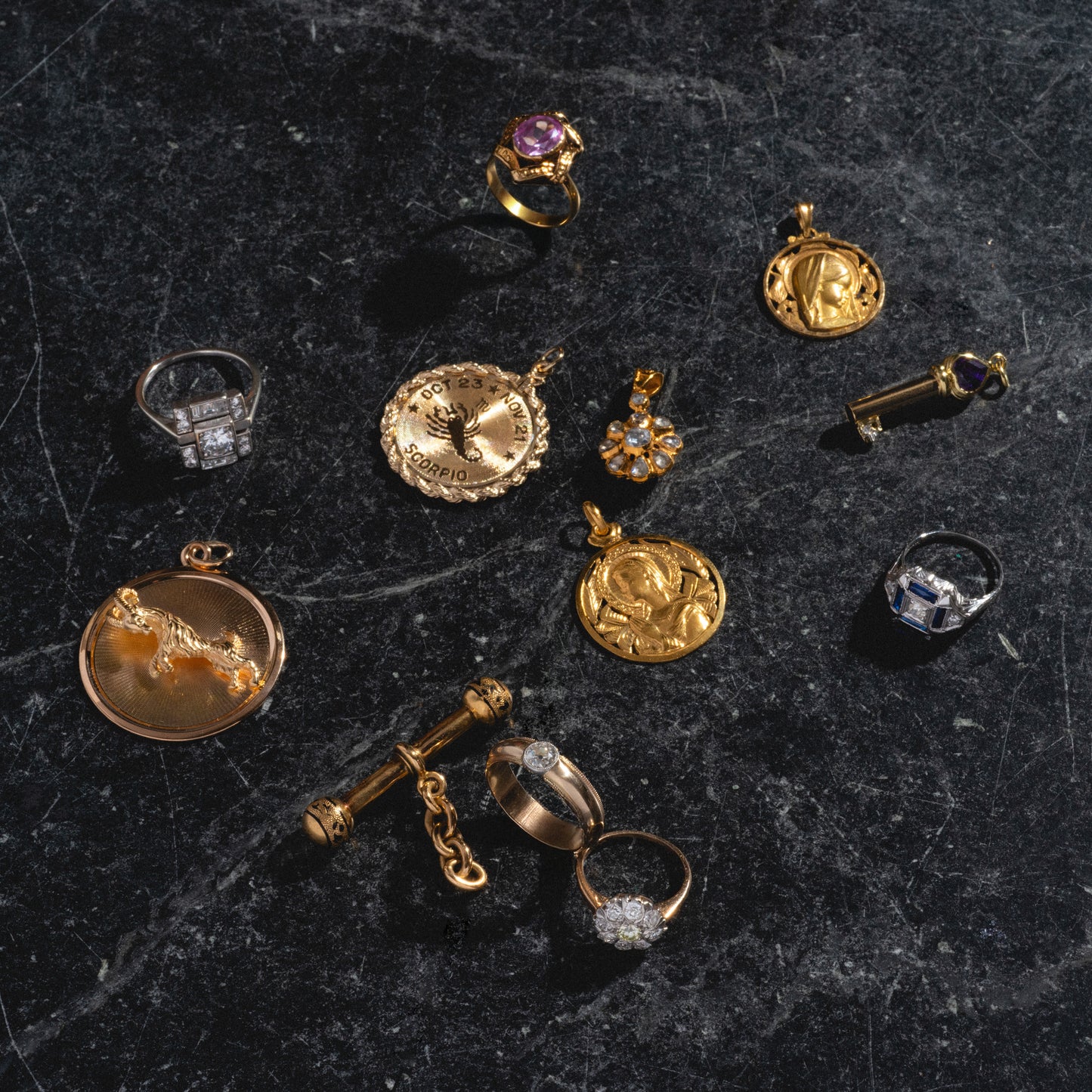 A Vintage 18k French T-Bar Dangle Charm is elegantly displayed on a dark marble surface, showcasing its classic yellow gold design.