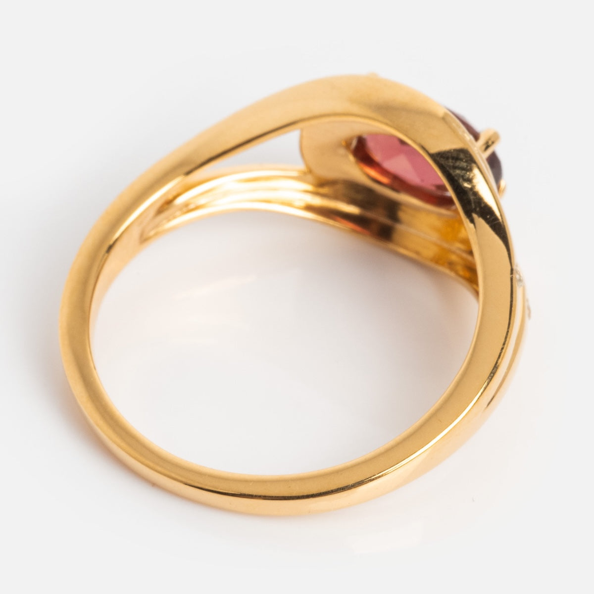 The Golden Age Garnet Cocktail Ring showcases a modern gold vermeil twisted band and a round deep pink garnet in a bezel setting, photographed on a plain white background.