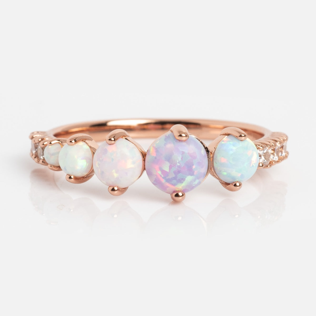 The Pastel Opal Shooting Star Ring features five round opals of varying sizes, the largest at the center, set in rose gold vermeil with small white accent stones along the band for celestial charm.