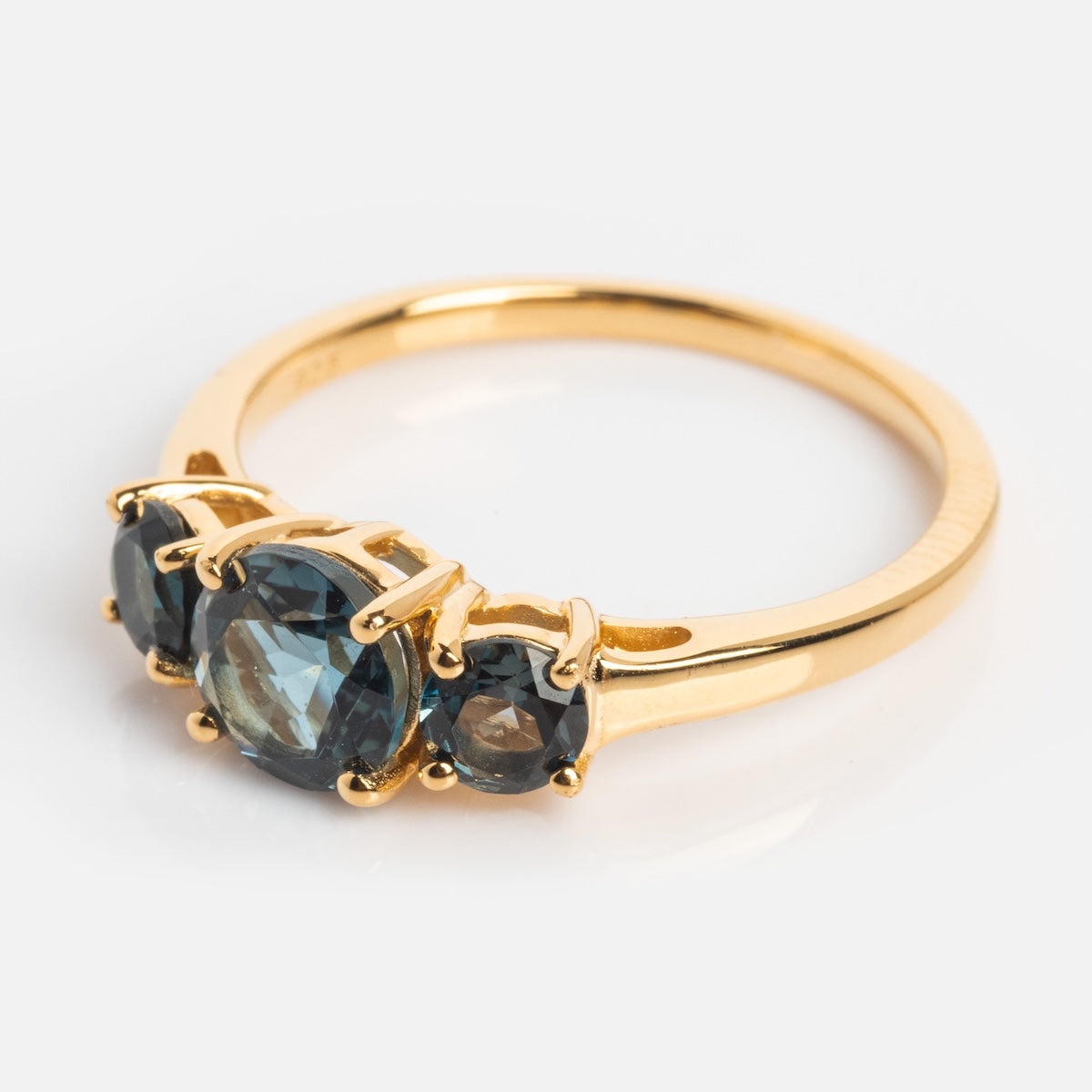 The London Blue Topaz Trilogy Ring is a vintage-inspired gold ring featuring three prong-set round London blue topaz stones—a large center gem flanked by two smaller ones—displayed on a white background.