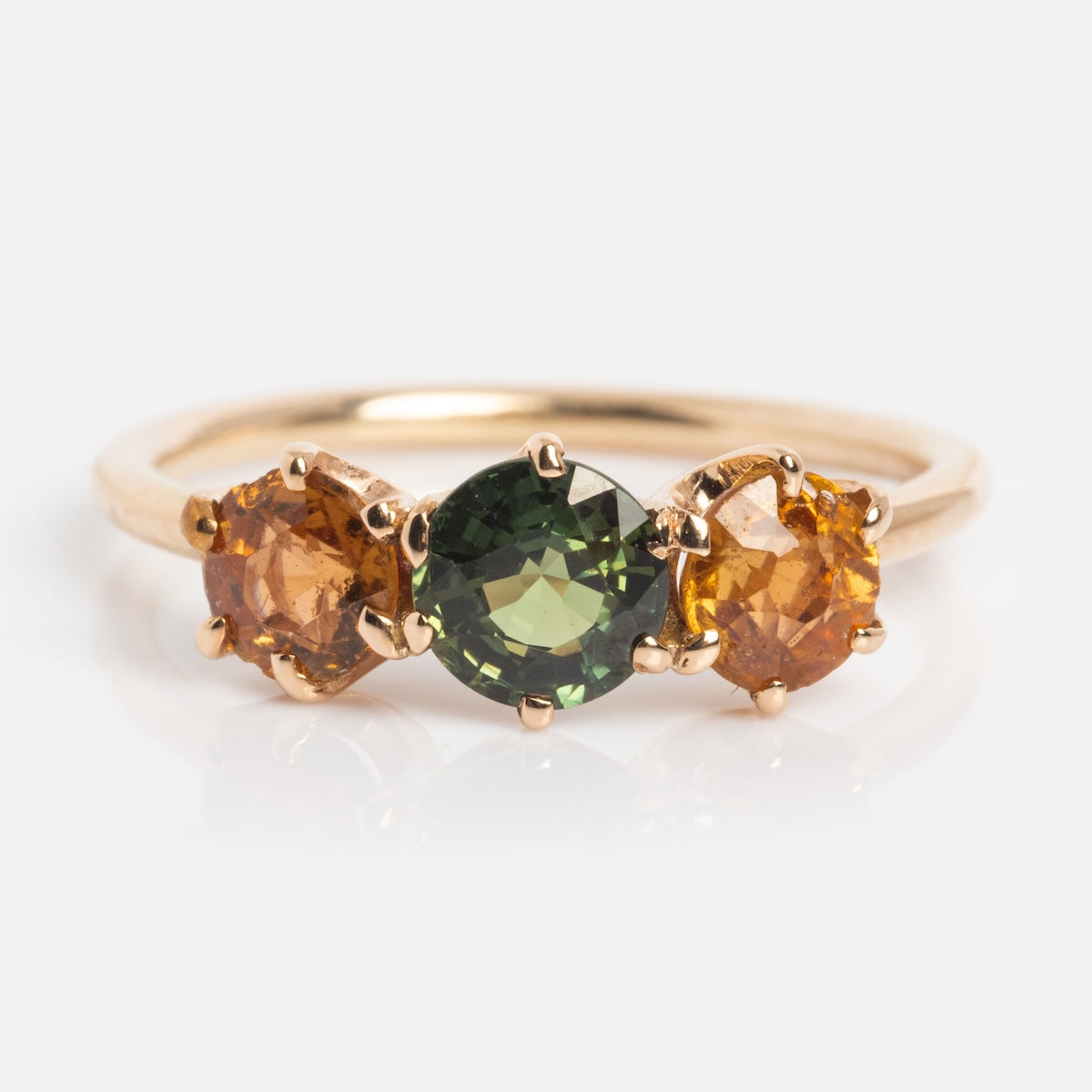 The Vintage 14k 1900s Tourmaline Trio Ring (Size 4.5) showcases three prong-set round tourmalines in green (center), orange (left), and yellow-orange (right) on yellow gold, displayed against a white background.