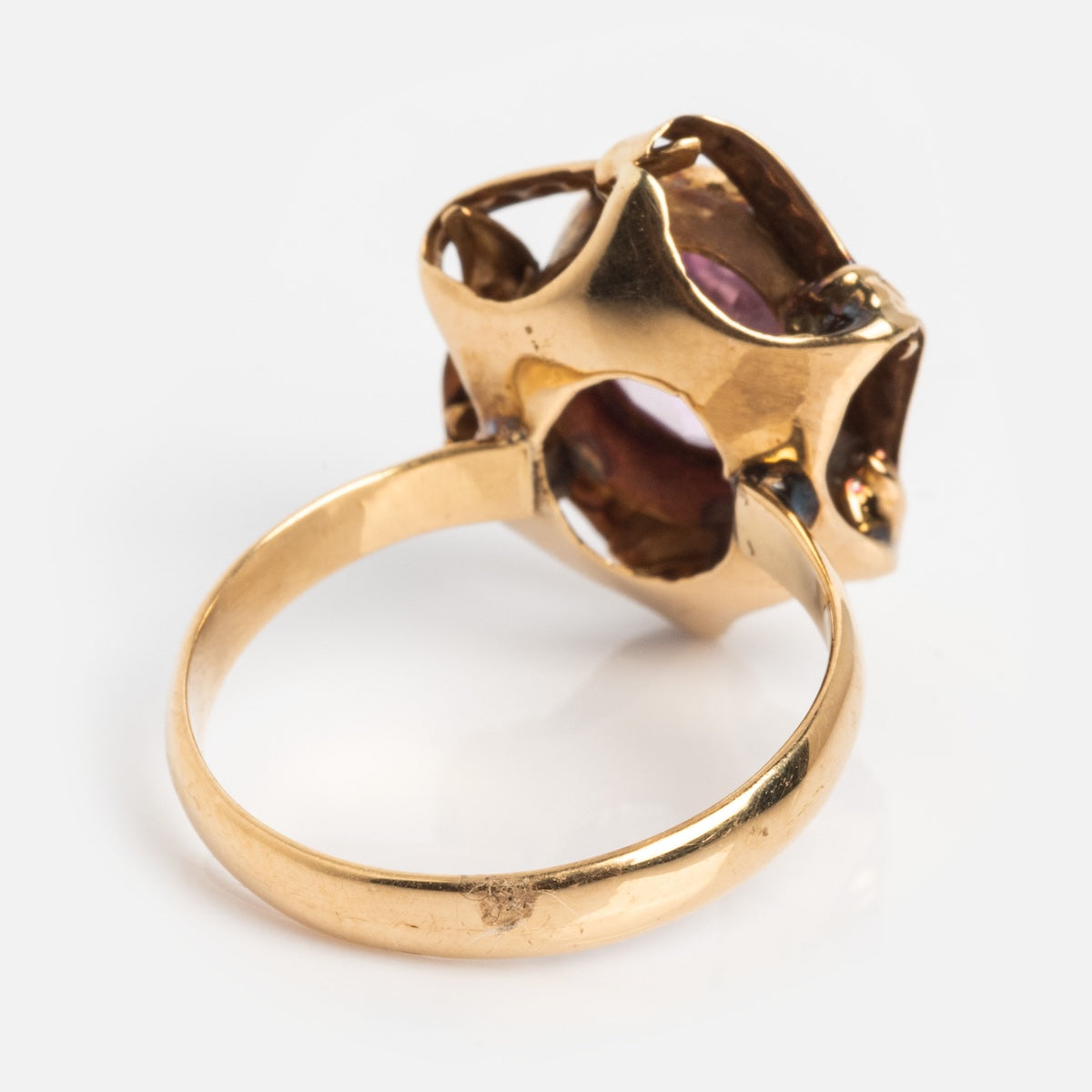 A Vintage 18k 1890s Opulent Pink Sapphire Cocktail Ring (Size 6.5) with an intricate, organic setting and pink sapphire, shown from the side on a white background, evokes the elegance of Gilded Age jewelry.