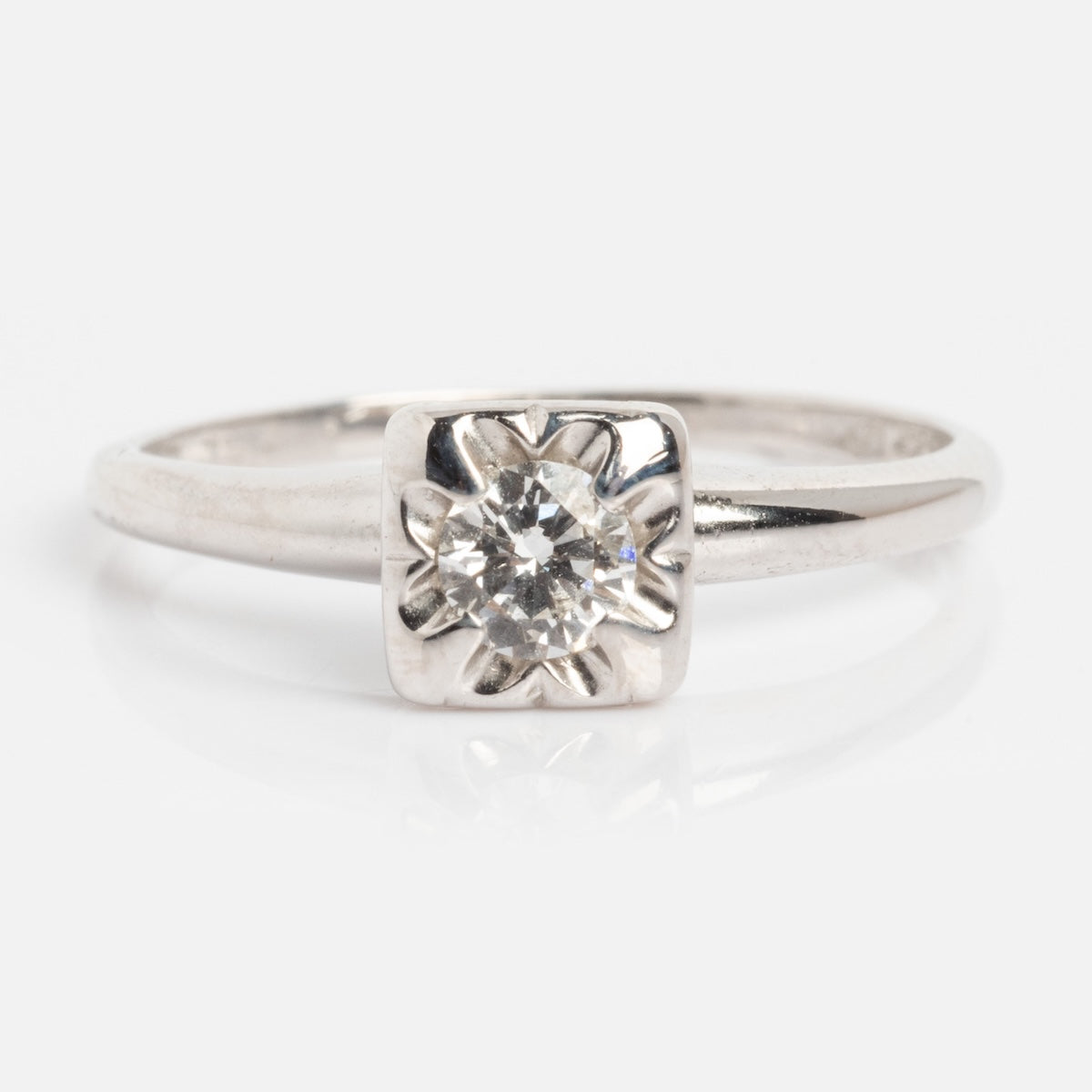A Vintage 14k 1940s White Gold Square Set Diamond Ring, size 7, features a round clear diamond in a square bezel with a starburst pattern, evoking classic charm and shown against a white background.