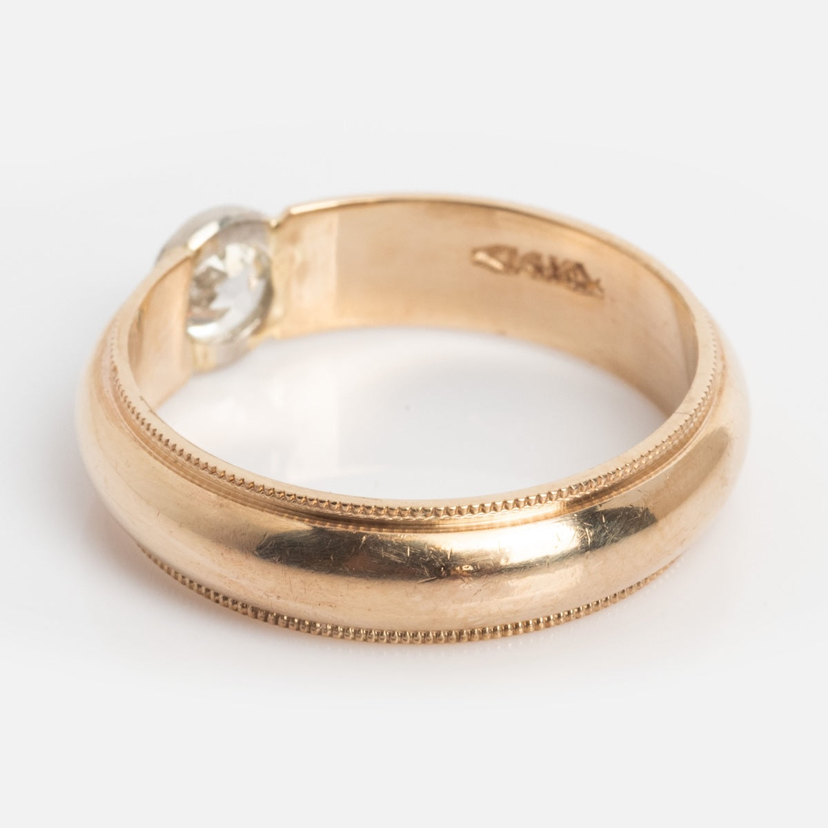 The Vintage 14k 1900s Euro Cut Diamond Classic Band, size 7.5, features a smooth, rounded yellow gold band with fine edge detailing and a single flush-set round diamond. Photographed on a white background.