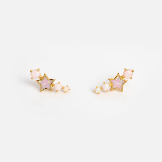 The Pastel Opal Shooting Star Studs feature a central star shape with pink stones, accented by smaller round pink opal studs arranged in a curve beside each star, shown against a plain white background.