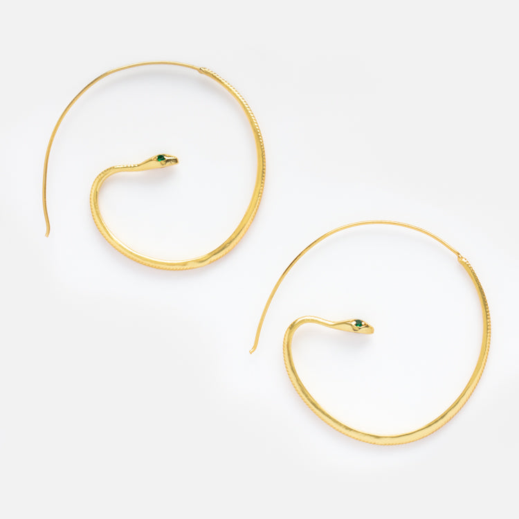 The Snake Hoop Earrings are 18k yellow gold plated with a delicate coil design and a small green zircon eye, shown on a plain white background.