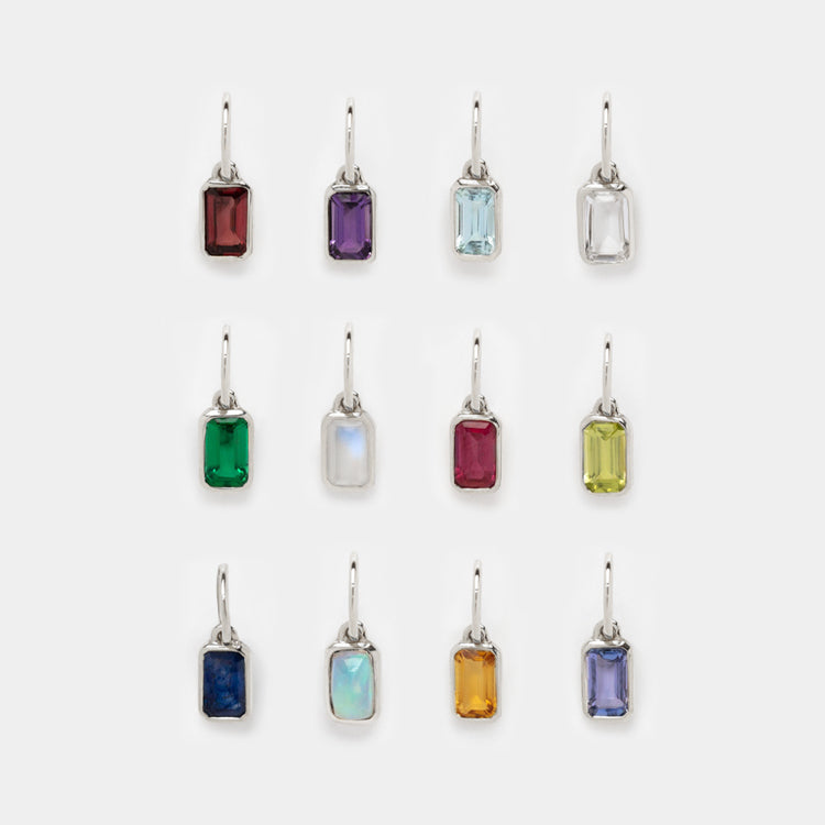 A set of twelve Solid Gold Birthstone Baguette Charms in white gold, each with a unique colored stone, arranged in three rows of four—a vibrant display perfect for your personalized jewelry collection.