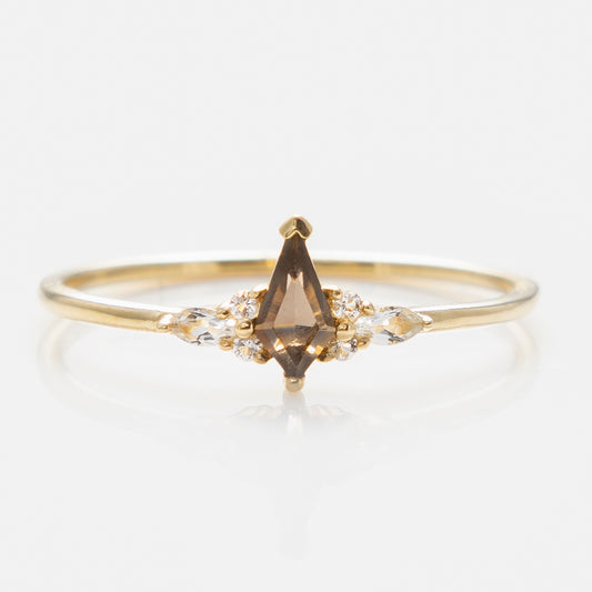The Solid Gold Smoky Quartz Shadow Kite Ring showcases a marquise smoky quartz center stone with white topaz accents on each side, set in yellow gold and displayed against a white background.