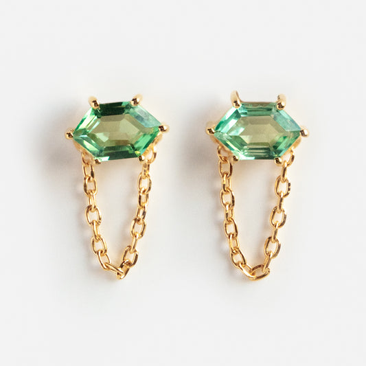 Introducing the Fern Green Topaz Chain Stud Earrings: gold vermeil earrings with green hexagonal topaz stones, each accented by a draped gold chain beneath the gem, displayed on a white background.