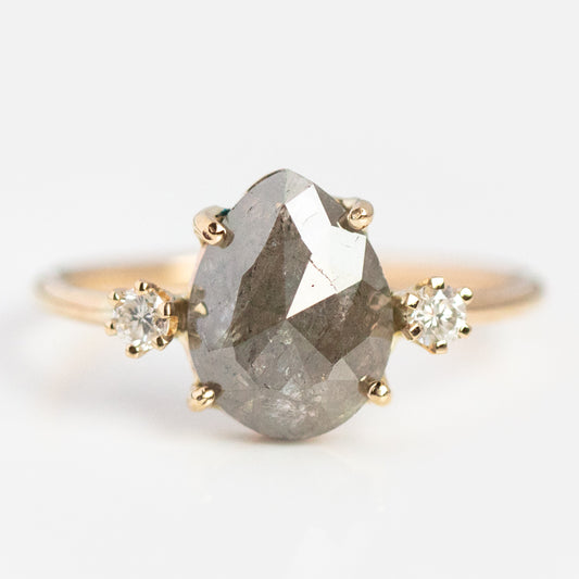 The Eternal Grey Diamond Ring features a large pear-shaped grey diamond at the center with two small round white diamonds on each side, set in yellow gold and displayed against a white background.
