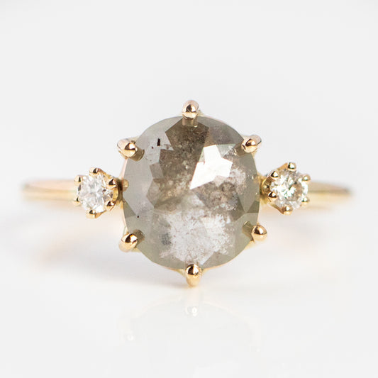 The Clair de Lune Grey Diamond Ring features a large oval rose cut gray diamond at the center, set in 14k gold and flanked by two small round white diamonds on each side, shown against a white background.