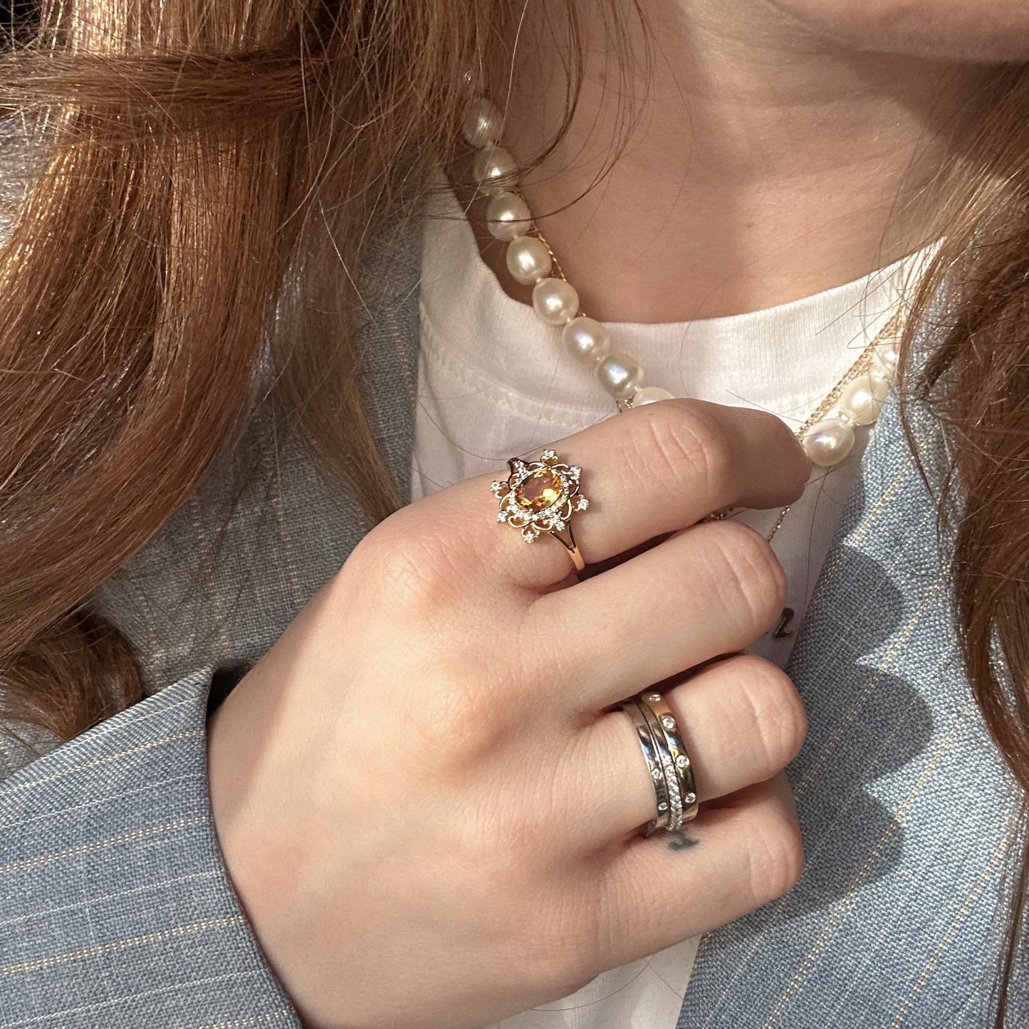A hand adorned with the 14k Vintage Inspired Citrine Statement Ring and a pearl necklace.