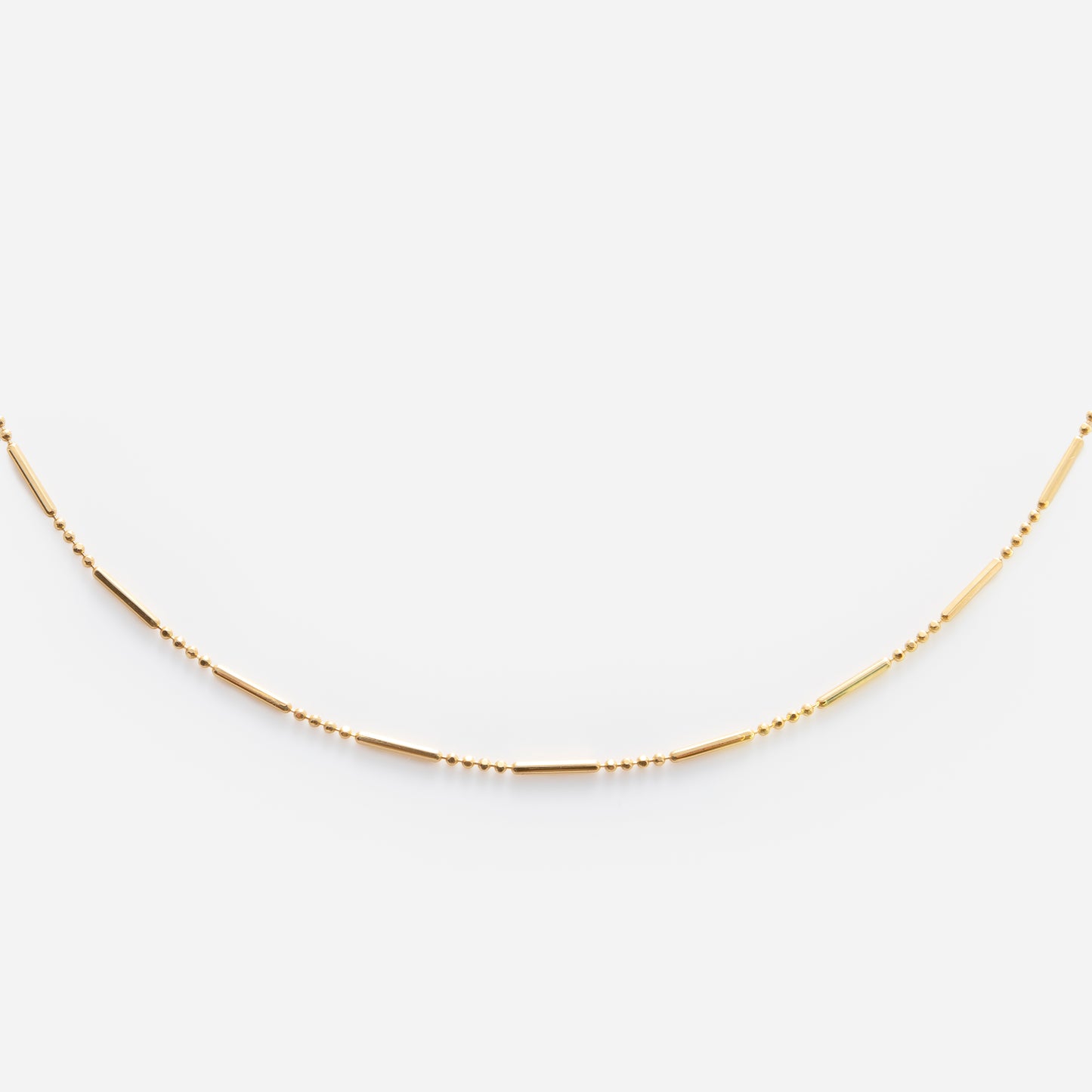 The Solid Gold Chain for Charms features small, evenly spaced beads and slender tubular segments, beautifully displayed on a white background.