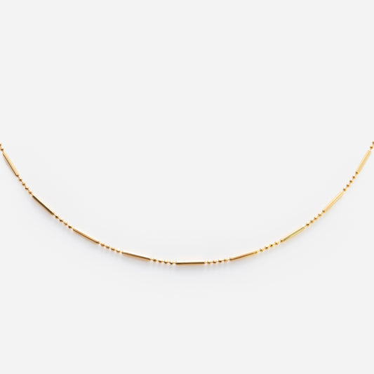 The Solid Gold Chain for Charms features small, evenly spaced beads and slender tubular segments, beautifully displayed on a white background.