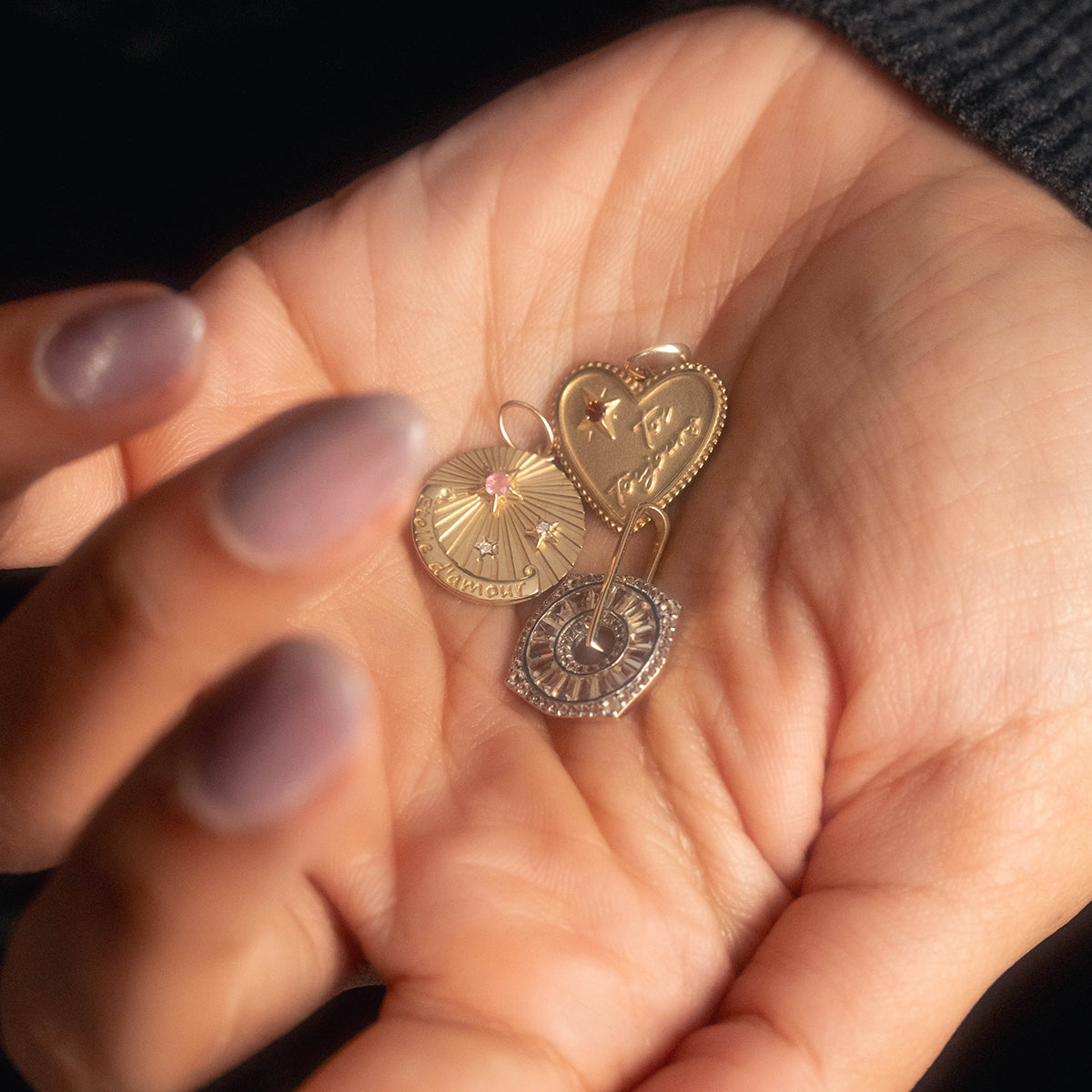 A manicured hand holds three gold charms, including the Solid Gold Coin Charm—an exclusive Local Eclectic piece perfect for jewelry lovers seeking unique, personalized styles.