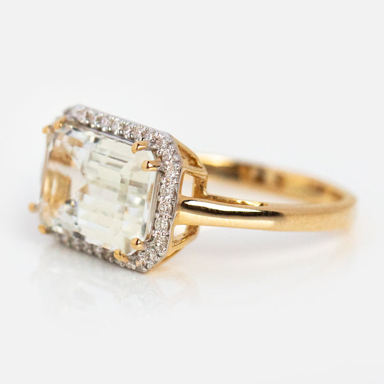 The 14k Solid Gold Diamond East West Baguette Ring features a large rectangular center stone with a halo of sparkling diamonds, crafted in solid gold and shown on a white background.