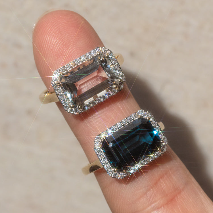 A close-up of the 14k Solid Gold Diamond East West Baguette Ring, featuring a rectangular diamond and sparkling halo, worn on a finger against a neutral background.