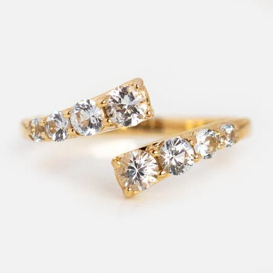 Two Solid Gold Sapphire Statement Wrap Rings, each crafted in 9k gold and adorned with graduated sparkling white sapphires, are displayed on a light background to highlight the elegance and brilliance of these standout rings.