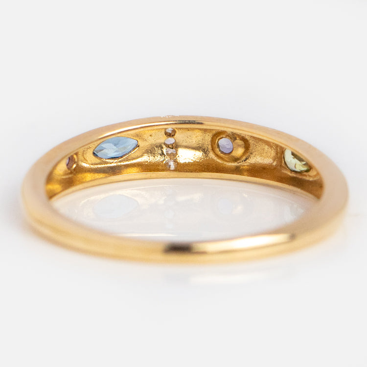 The Solid Gold Pizza Acrostic Ring features small blue, green, and clear gemstones on its inner band, embodying the acrostic jewelry style and photographed against a white background.