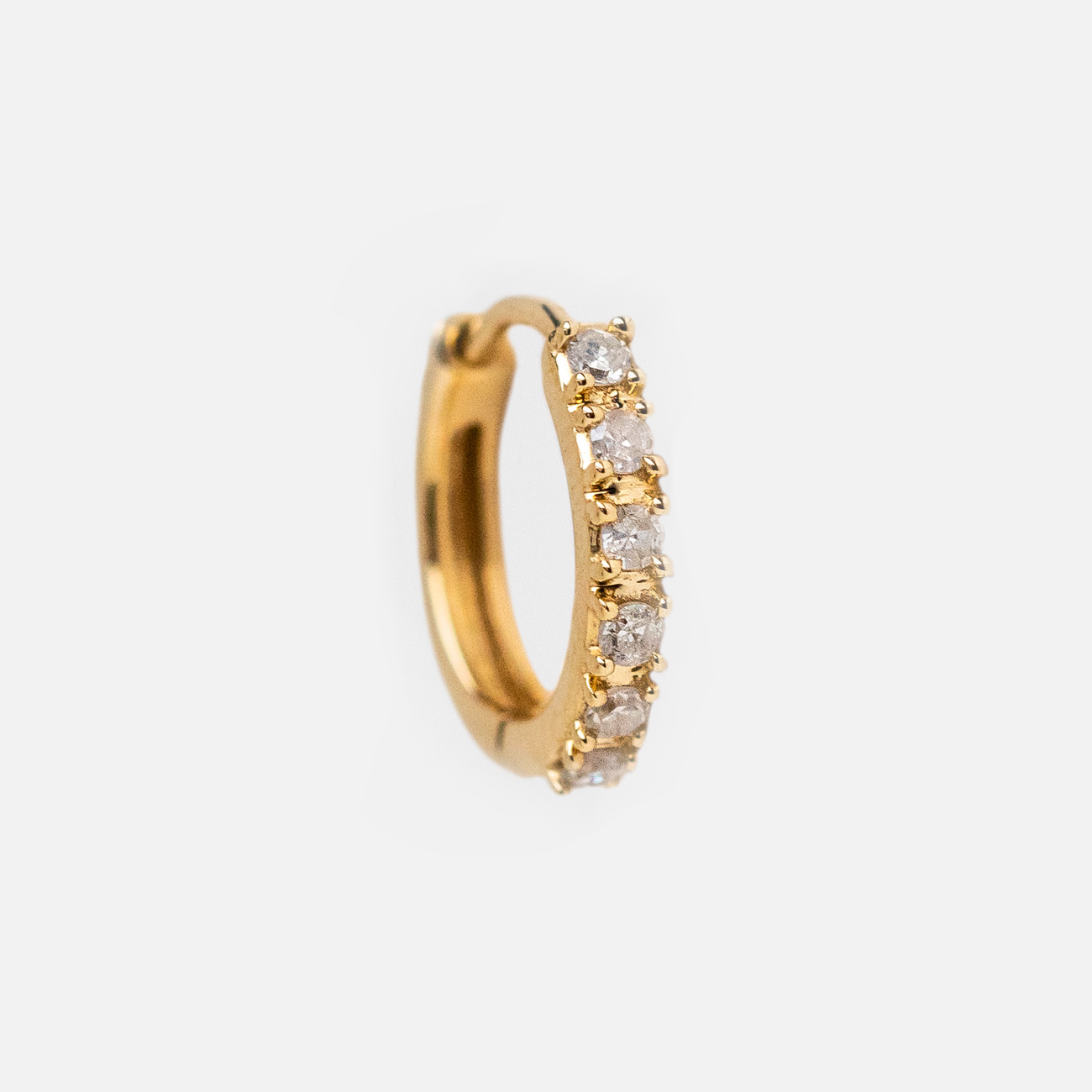 The Solid Gold Diamond Huggie Hoops feature seven small, round-cut diamonds set along the front edge and are showcased against a plain white background.