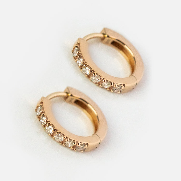 Exclusive to Local Eclectic, the Solid Gold Diamond Huggie Hoops Sample are small 10k yellow gold hoops featuring a row of brilliant cut diamonds along the front, shown on a plain white background.