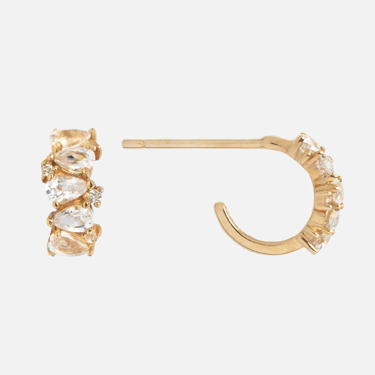 Solid Gold Ombre Birthstone Huggie Hoops featuring multiple clear, oval-cut gemstones set along the edge; one hoop is shown front-on and the other from the side, showcasing their sparkling elegance.