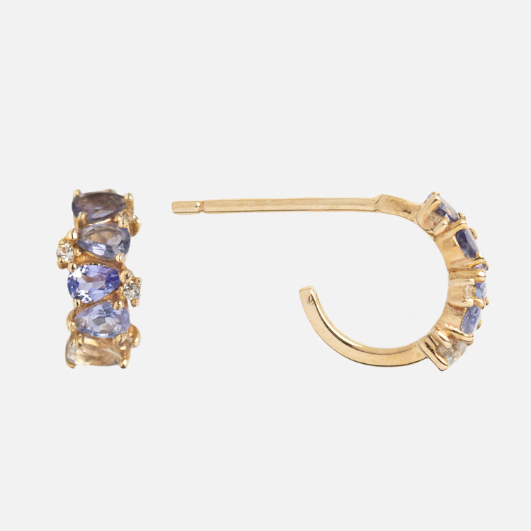 The Solid Gold Ombre Birthstone Huggie Hoops feature 9k gold and five oval blue gemstones with clear accents, shown on a plain white background—an elegant choice for birthstone earrings.