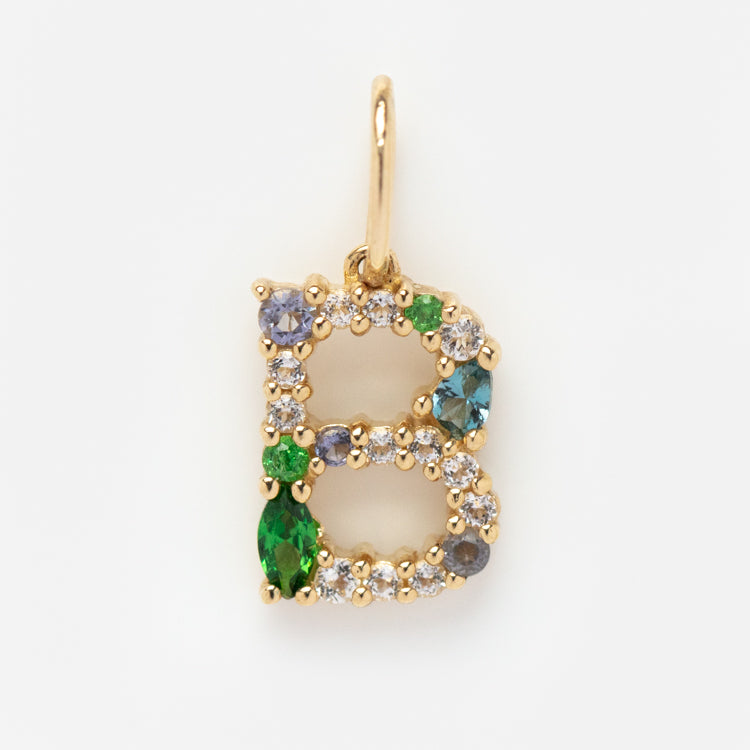 The Solid Gold Gemstone Letter Charm features a gold letter B encrusted with multicolored gemstones—green, blue, and clear—creating a stunning accessory displayed on a plain white background.