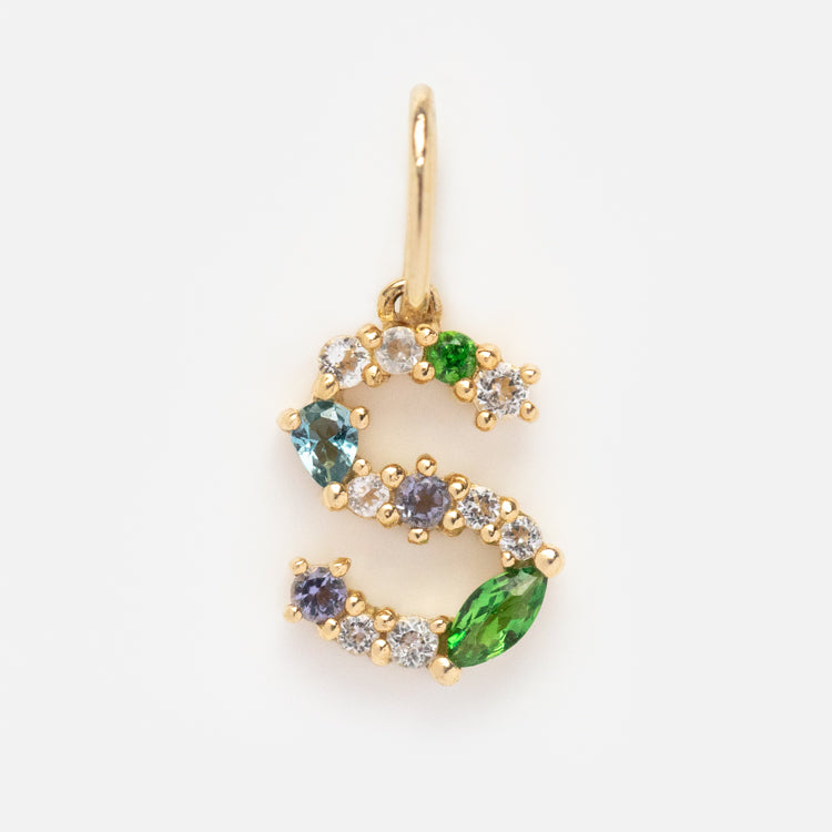 The Solid Gold Gemstone Letter Charm is an S-shaped gold pendant adorned with round and marquise-cut green, blue, and clear gemstones, displayed on a plain white background.