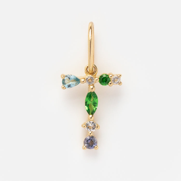 The Solid Gold Gemstone Letter Charm features a gold letter T adorned with green, blue, and clear gemstones, displayed against a white background.