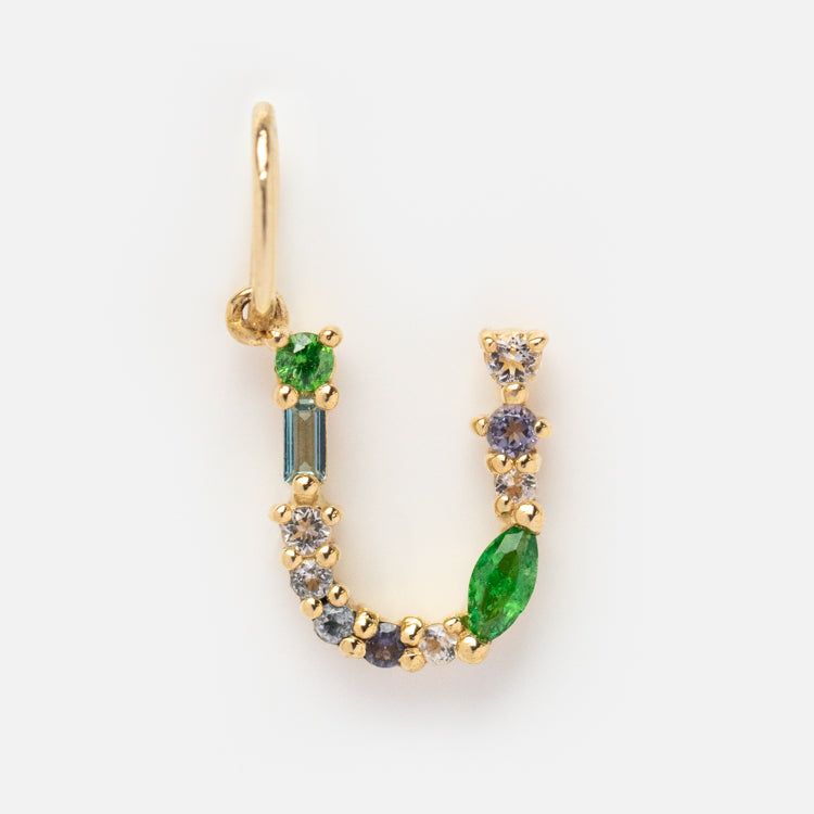 The Solid Gold Gemstone Letter Charm, shaped like the letter U, features small green, blue, and clear stones set in solid gold on a white background for a personalized touch.