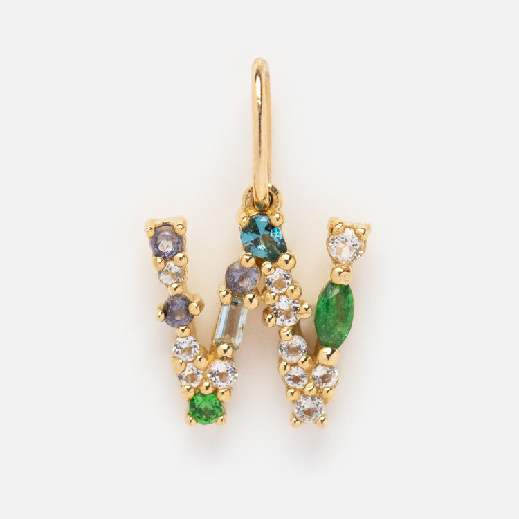 The Solid Gold Gemstone Letter Charm in a W shape dazzles with green, blue, purple, and clear stones for a brilliant multicolored look.