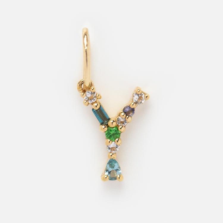 The Solid Gold Gemstone Letter Charm features a gold Y pendant adorned with multicolored gemstones—green, blue, and clear—for a vibrant look, displayed on a plain white background.