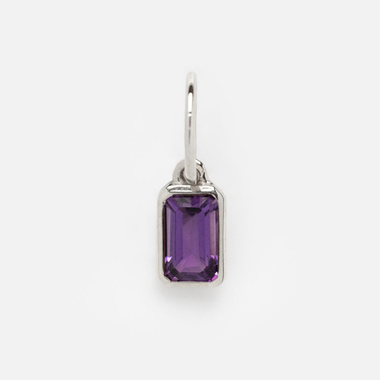 The Solid Gold Birthstone Baguette Charm in White Gold features an emerald-cut purple gemstone in a sleek bezel setting with a small circular bail, displayed on a plain white background.