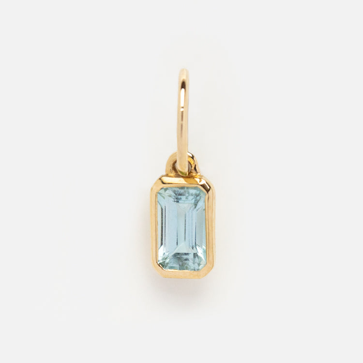 The Solid Gold Birthstone Baguette Charm features a rectangular, emerald-cut light blue gemstone at its center, shown on a plain white background—a timeless, personalized jewelry piece.