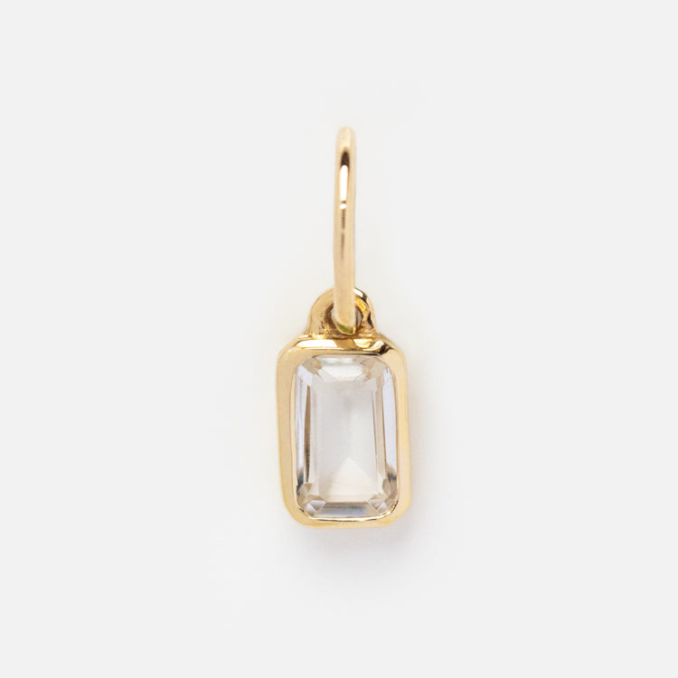 The Solid Gold Birthstone Baguette Charm is a classic gold pendant with a rectangular clear gemstone, beveled edges, and a simple gold frame—ideal for personalized jewelry.