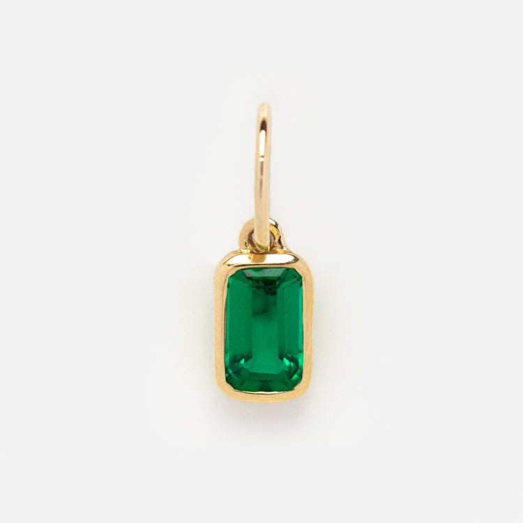 The Solid Gold Birthstone Baguette Charm features a rectangular emerald-green pendant in a gold bezel with a loop for chains, ideal for personalized jewelry, displayed on a plain white background.