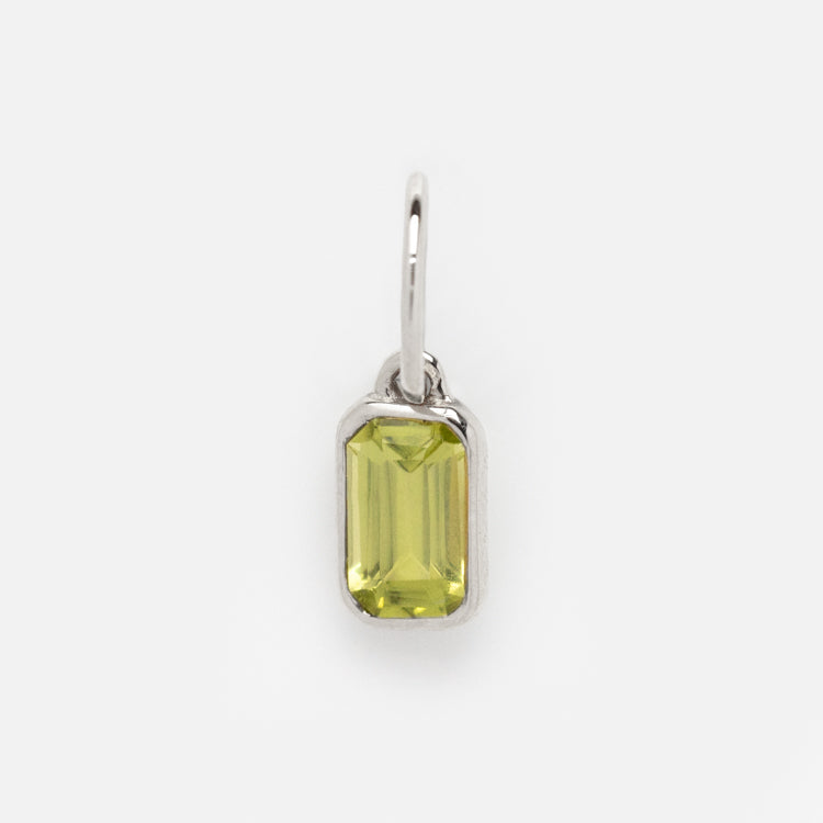 A Solid Gold Birthstone Baguette Charm in White Gold featuring a rectangular, faceted light green gemstone with beveled edges set in a simple frame—an elegant, timeless piece perfect for personalized jewelry.