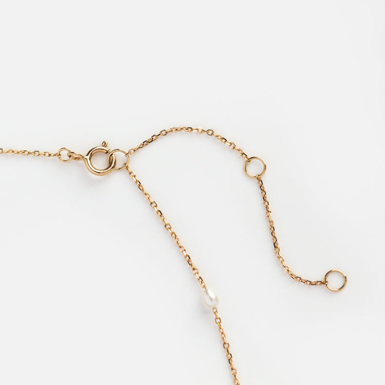 The Solid Gold Pearl Lariat Necklace features several small circular links along a delicate gold chain with a spring ring clasp, offering an elegant update to the classic pearl necklace, displayed on a white background.