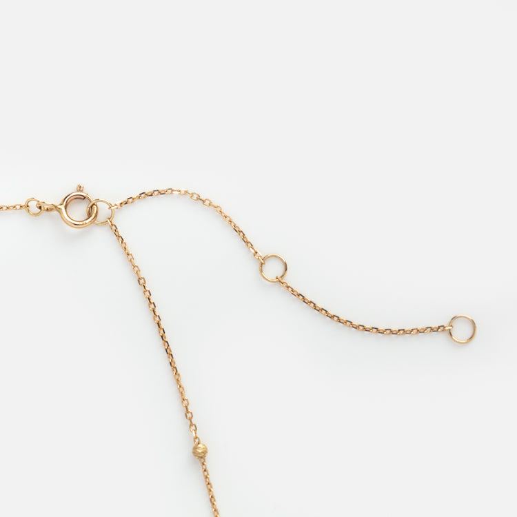 The Solid Gold Beaded Lariat Necklace features three adjustable loops and a spring ring clasp, shown on a plain white background.