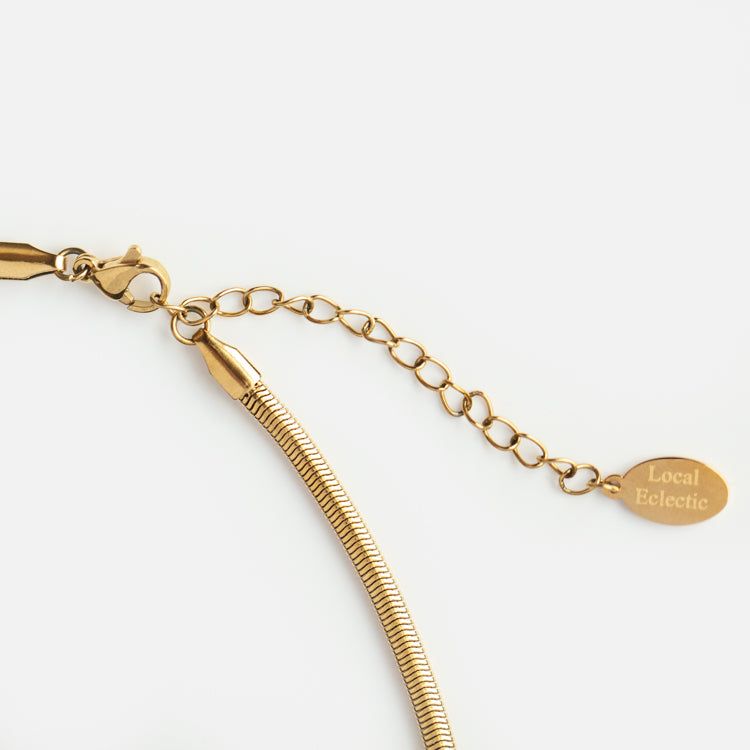Close-up of the Classic Snake Chain Necklace: a gold plated necklace with an adjustable snake chain and a small oval tag engraved Local Eclectic, shown on a white background.