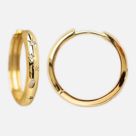 The Star Crossed Celestial Hoop Earrings in gold vermeil feature two hoops, with one accented by small cubic zirconia stones arranged in star shapes, displayed against a plain white background.