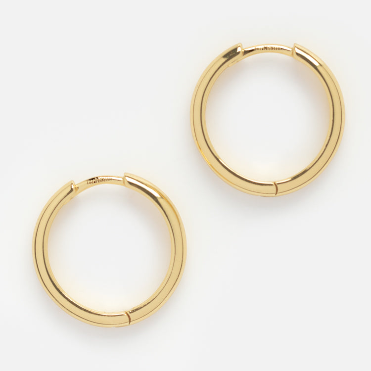 The Classic Small Hoops, a pair of simple and shiny gold earrings, are displayed on a plain white background. Timeless and minimalist, these hoops are perfect as versatile jewelry for any occasion.